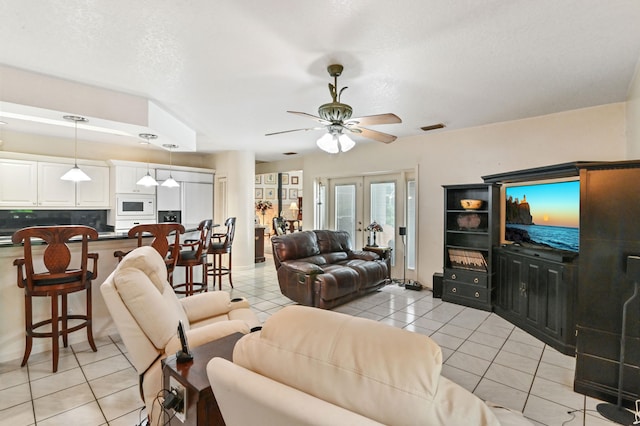 tiled living room featuring french doors, ceiling fan, and a textured ceiling