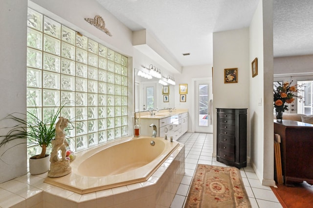 bathroom featuring vanity, a textured ceiling, tiled bath, and tile patterned flooring