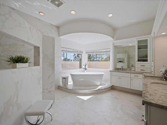 bathroom featuring vanity, a bathtub, and tile walls