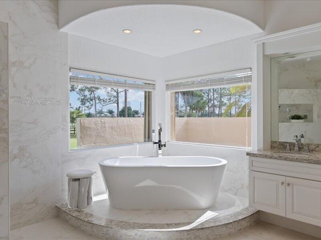 bathroom with a bath, plenty of natural light, and vanity