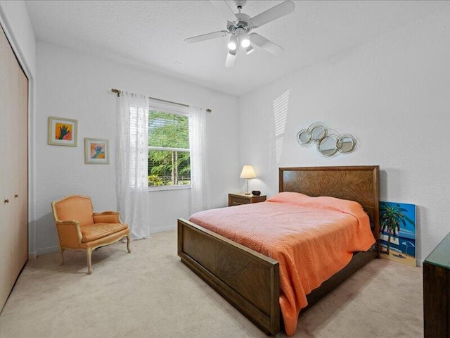 bedroom with a textured ceiling, light colored carpet, ceiling fan, and a closet