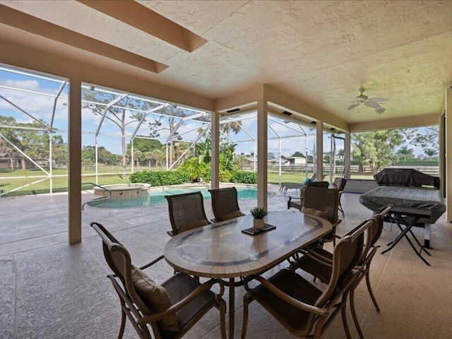 view of patio featuring glass enclosure, ceiling fan, and a pool with hot tub