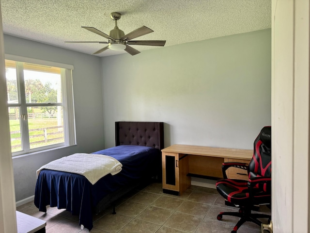 bedroom with a textured ceiling, ceiling fan, and tile patterned floors