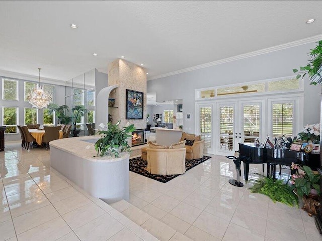 tiled living room with an inviting chandelier, a large fireplace, ornamental molding, and french doors