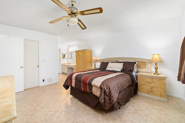 bedroom featuring a textured ceiling, ceiling fan, light tile patterned floors, and ensuite bath