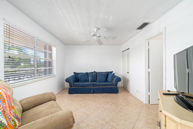 tiled living room with ceiling fan and a textured ceiling