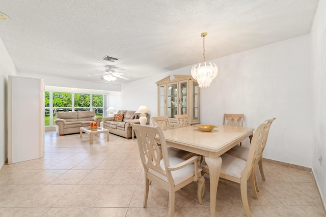 dining space featuring ceiling fan with notable chandelier, a textured ceiling, and light tile patterned floors