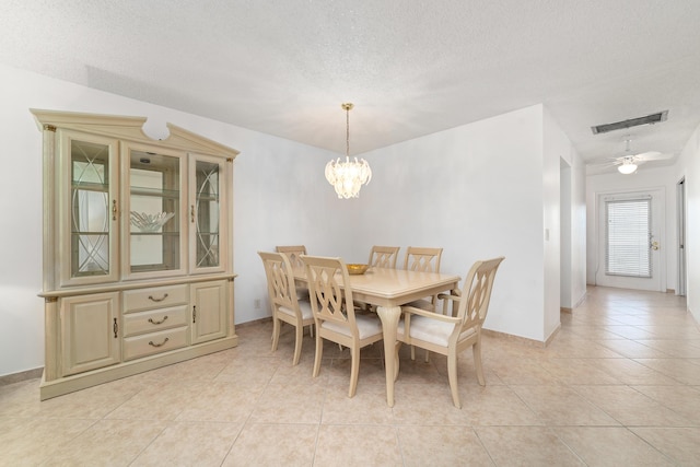 dining room with light tile patterned floors, ceiling fan with notable chandelier, and a textured ceiling