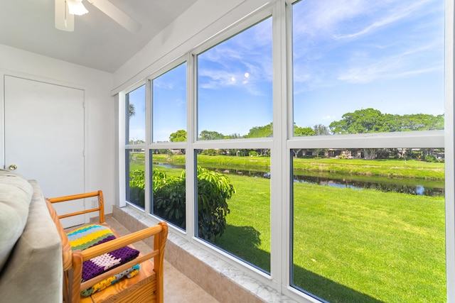 sunroom with ceiling fan and a water view