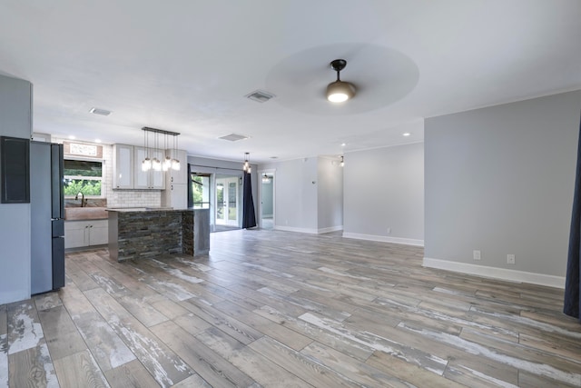 kitchen with refrigerator, ceiling fan, light hardwood / wood-style floors, decorative backsplash, and pendant lighting