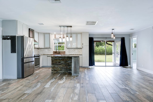 kitchen with a center island, wood-type flooring, tasteful backsplash, and stainless steel appliances