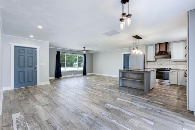 kitchen with stainless steel stove, custom range hood, light wood-type flooring, a center island, and white refrigerator