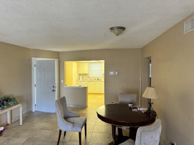 dining space featuring visible vents, a textured ceiling, and baseboards