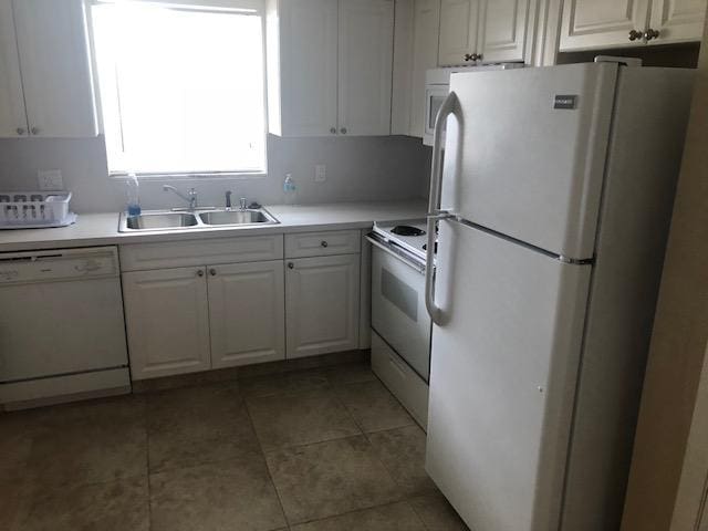 kitchen featuring white appliances, light tile patterned floors, white cabinets, light countertops, and a sink