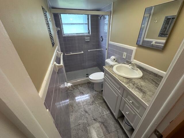 bathroom featuring a shower stall, toilet, and vanity