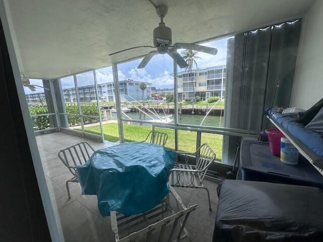 sunroom with a water view and ceiling fan