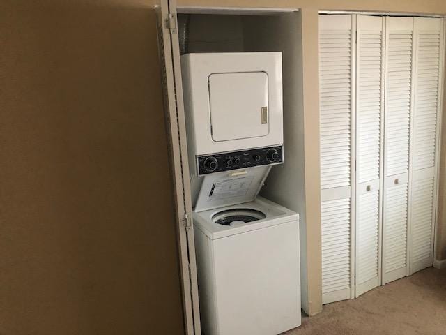 laundry room featuring stacked washer and clothes dryer, light colored carpet, and laundry area