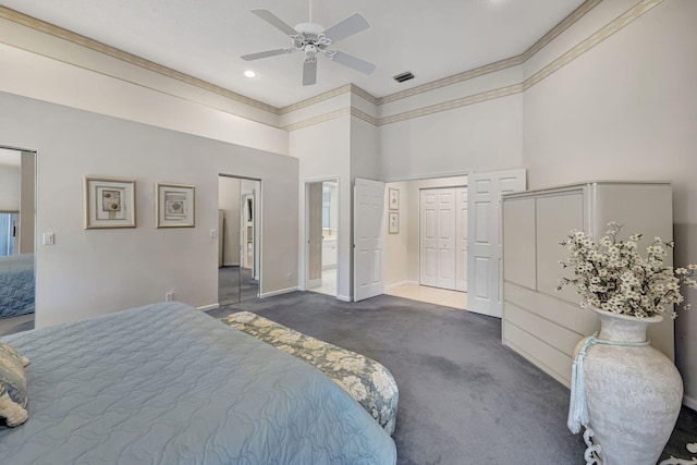 carpeted bedroom with ceiling fan, a towering ceiling, ornamental molding, and two closets