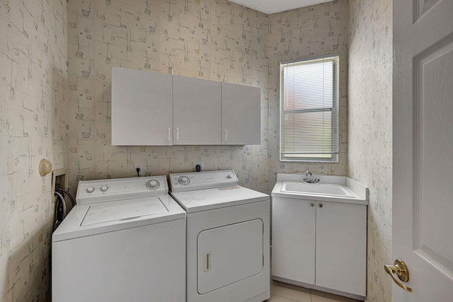 washroom with cabinets, independent washer and dryer, and sink