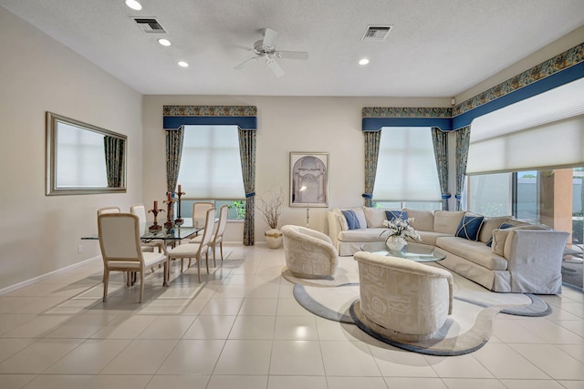 living room featuring ceiling fan, light tile patterned flooring, and a textured ceiling