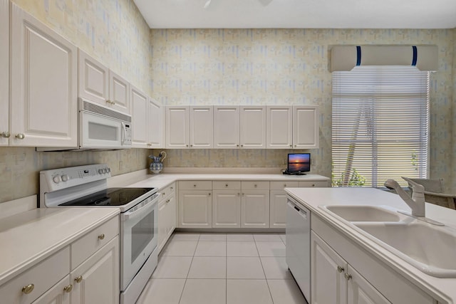 kitchen featuring light tile patterned floors, white appliances, white cabinetry, and sink