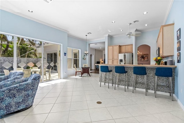 kitchen with ceiling fan, stainless steel appliances, light brown cabinetry, and ornamental molding