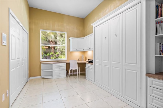 unfurnished office featuring built in desk and light tile patterned flooring