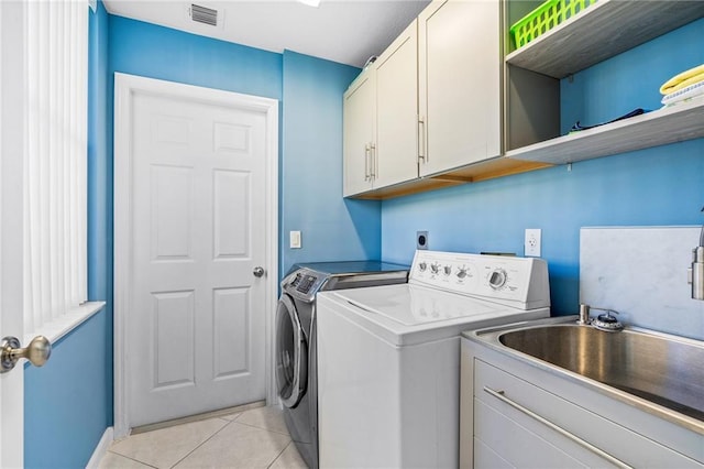 laundry area with light tile patterned floors, sink, independent washer and dryer, and cabinets