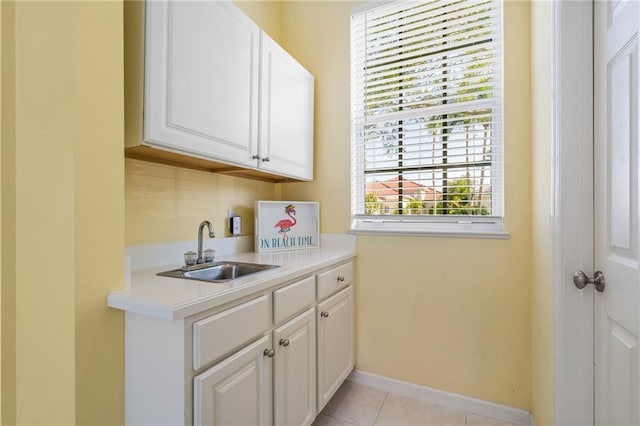 kitchen featuring light tile patterned floors, sink, and white cabinets