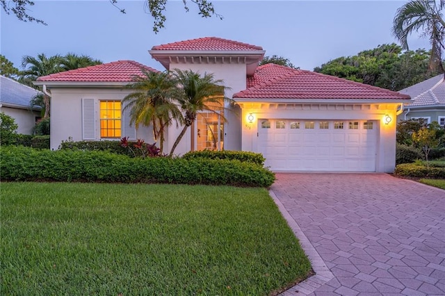 mediterranean / spanish-style house featuring a garage and a yard