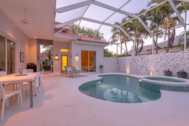 view of swimming pool with an in ground hot tub, glass enclosure, ceiling fan, and a patio