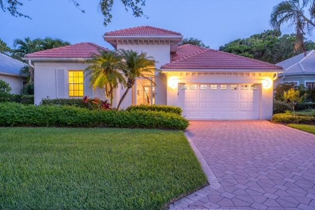 mediterranean / spanish-style home with a garage and a yard