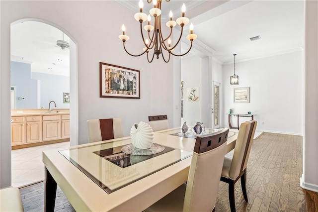 tiled dining room with sink, ceiling fan with notable chandelier, and ornamental molding