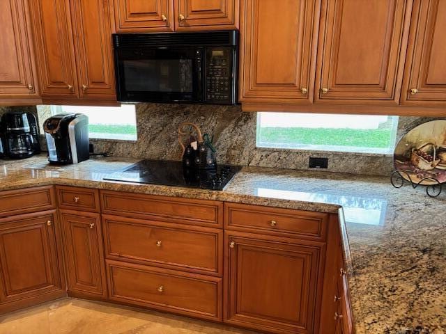 kitchen featuring light stone countertops, light tile patterned flooring, and black appliances