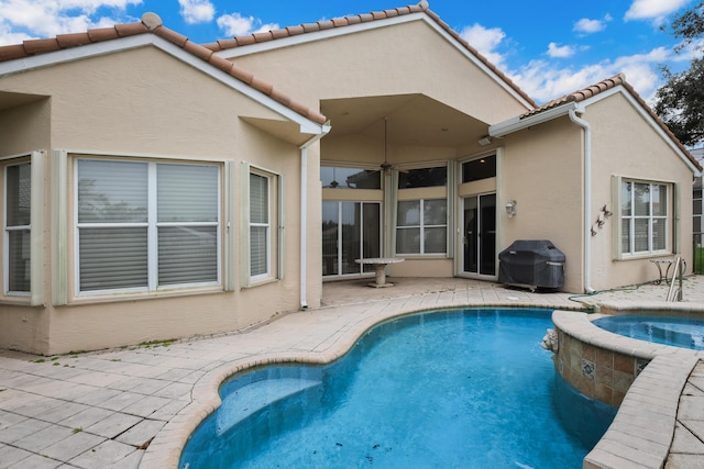 exterior space with an in ground hot tub, a patio, and grilling area