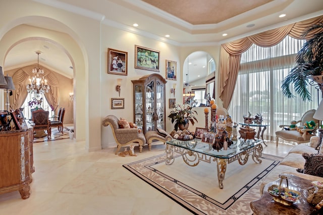 living room featuring a notable chandelier, a raised ceiling, ornamental molding, and a towering ceiling