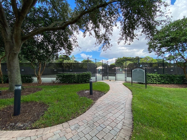 view of community featuring a lawn and tennis court