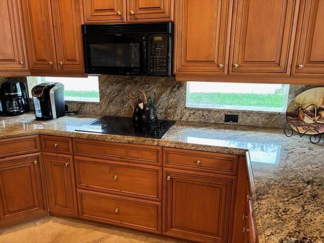 11420 Ohanu Cir, Boynton Beach, FL 33437 - kitchen featuring black appliances, light stone counters, brown cabinetry, and backsplash