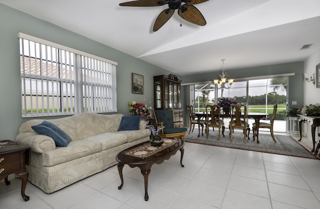 tiled living room with ceiling fan with notable chandelier and vaulted ceiling