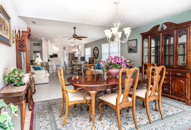 dining space with ceiling fan with notable chandelier and light tile patterned floors