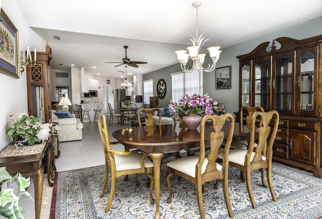 tiled dining room with ceiling fan with notable chandelier