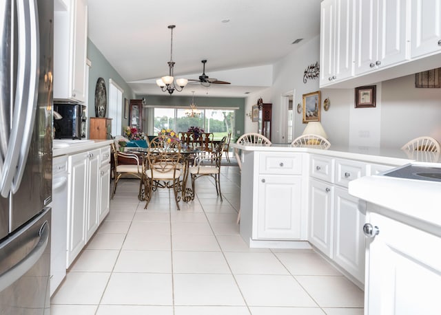 kitchen with pendant lighting, stainless steel refrigerator, lofted ceiling, and white cabinets