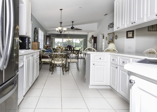 kitchen featuring hanging light fixtures, light tile patterned floors, stainless steel refrigerator, a notable chandelier, and white cabinets