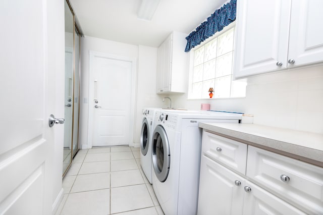 laundry room featuring washing machine and dryer, cabinets, and light tile patterned floors