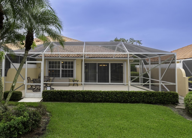 back of property featuring a yard, a patio, and glass enclosure