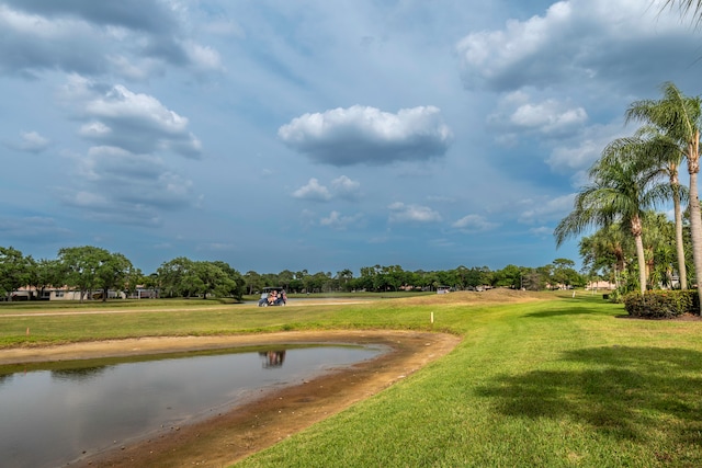 surrounding community with a water view and a lawn