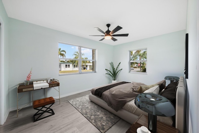 bedroom with ceiling fan, light hardwood / wood-style flooring, and multiple windows