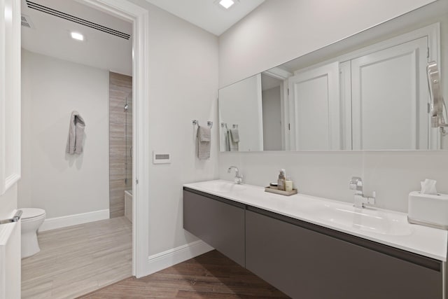 full bathroom featuring toilet, hardwood / wood-style floors, vanity, and washtub / shower combination