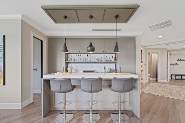 kitchen featuring a kitchen bar, light hardwood / wood-style flooring, gray cabinetry, and pendant lighting