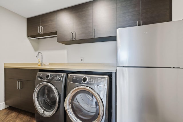 laundry area featuring sink, dark hardwood / wood-style flooring, and washing machine and clothes dryer